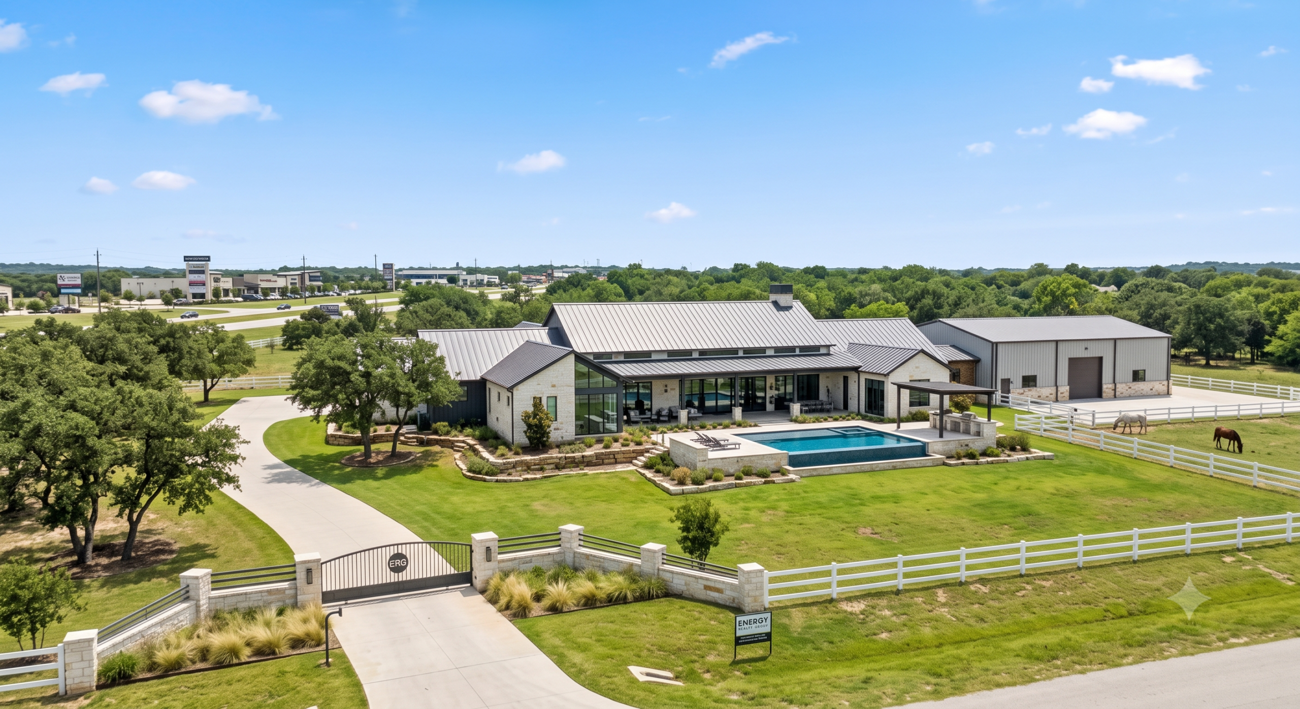 An aerial view of a luxury modern Texas Hill Country estate with a gated entry, private swimming pool, and detached custom workshop on acreage, positioned near the growing commercial corridor between Hudson Oaks and Weatherford.